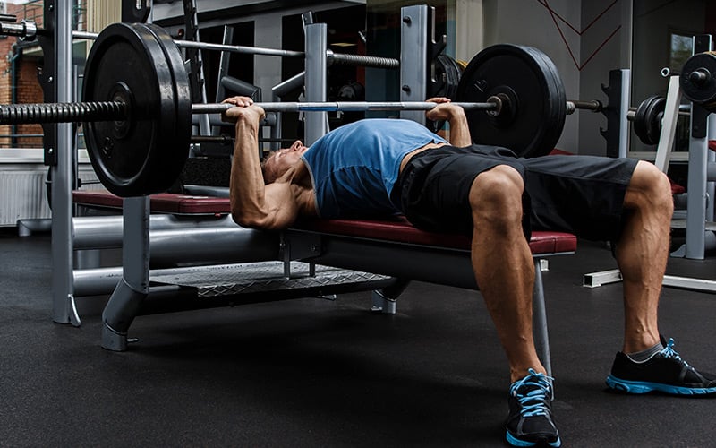 Strong man doing barbell bench press in the gym