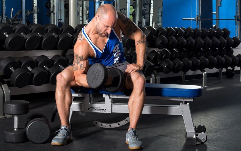 Muscle man doing dumbbell bicep curl in the gym