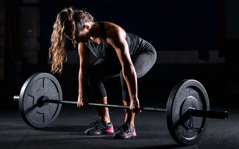 Woman setting up for a deadlift in a gym.