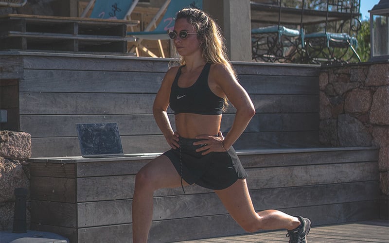 Female working out outside doing bodyweight walking lunges.
