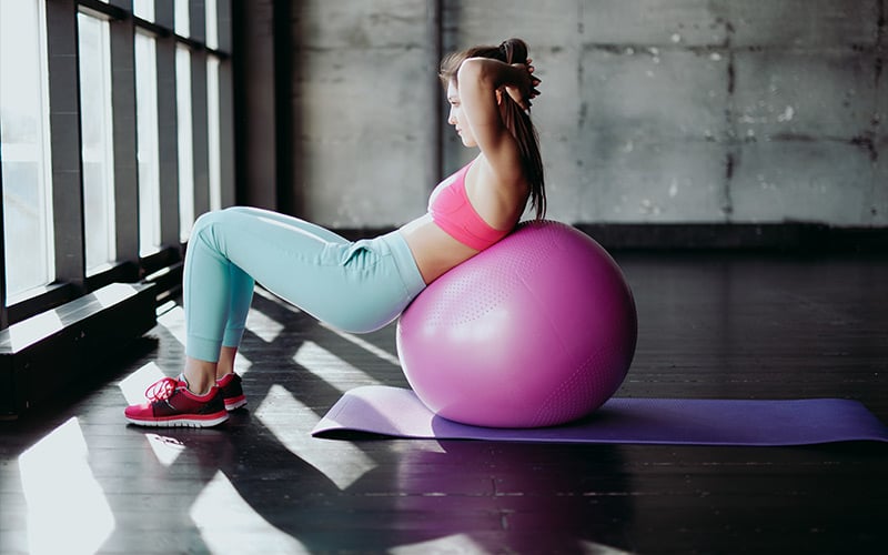 Fit female doing crunches on the exercise ball.