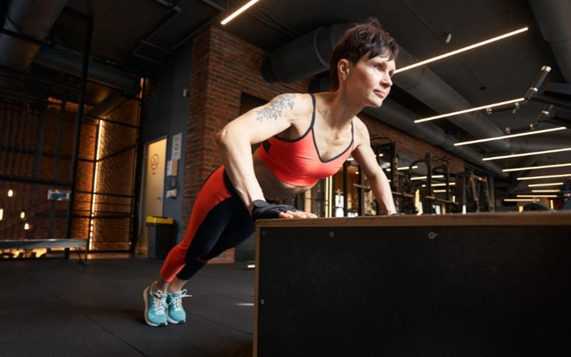 Lean female doing pushups in the gym.