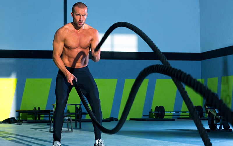 Athlete performing HIIT cardio with battle ropes