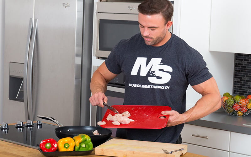 Athlete in M&S Grey Spinal Cooking Chicken and Veggies for Meal Prep