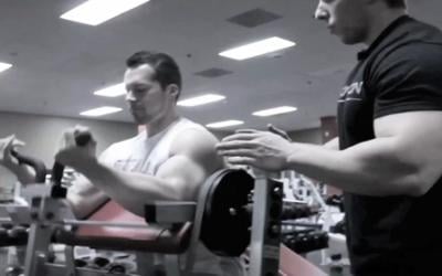 Fit man doing preacher curl in the gym