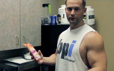 Man in tank top holding supplements
