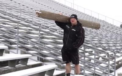 Strongman standing outside holding large log