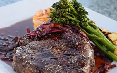 Close up of grilled steak and broccoli served on a white plate. 