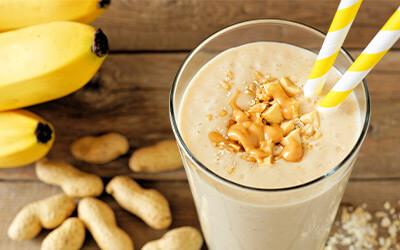 Close up of peanut butter and banana smoothie sitting on top of a wooden table.