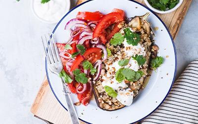 Aerial shot of roasted eggplant topped with parsley and paired with onions and tomatoes.