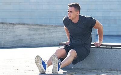 Man performing beginner bodyweight tricep dip outside on bench.