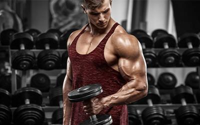Close up of muscular man doing dumbbell bicep curls in the gym.
