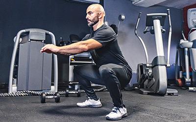Man performing a bodyweight air squat in the gym.