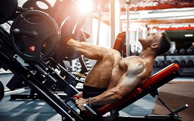 Muscular man doing heavy leg presses in the gym