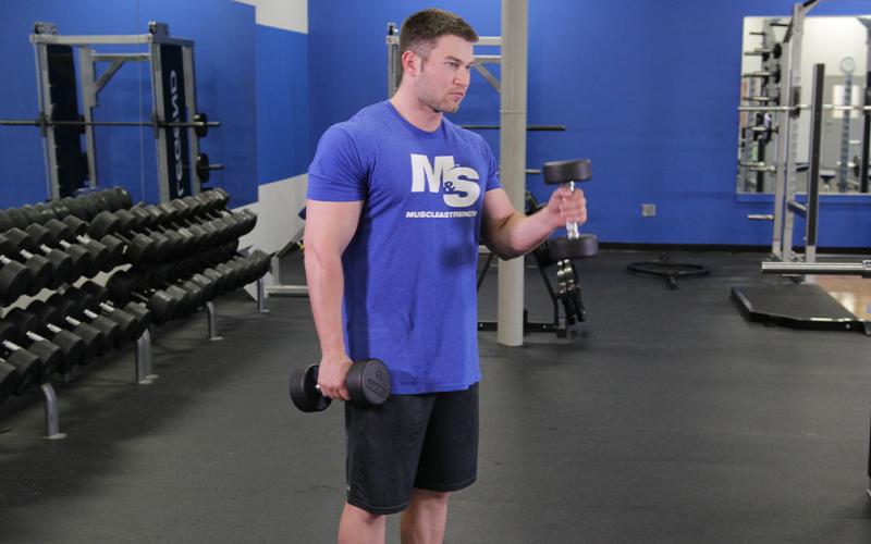 Fit man doing an alternating standing hammer curl.