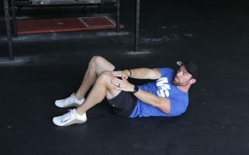 Fit man doing alternating reach and catches in the gym.