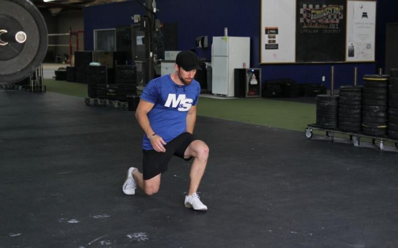 Fit man doing a Bodyweight Walking Lunge in the gym.