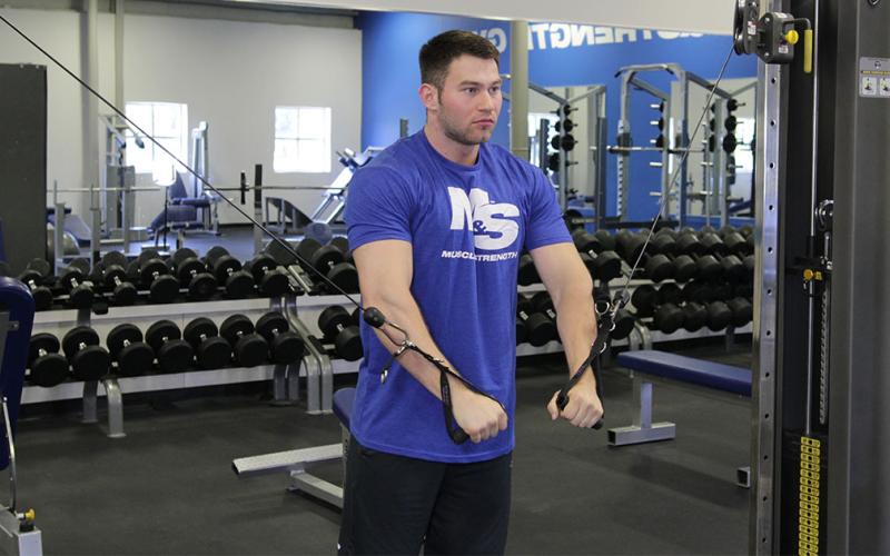 Fit man doing a cable inner chest press in the gym