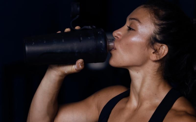 Swolverine athlete drinking out of black shaker bottle.