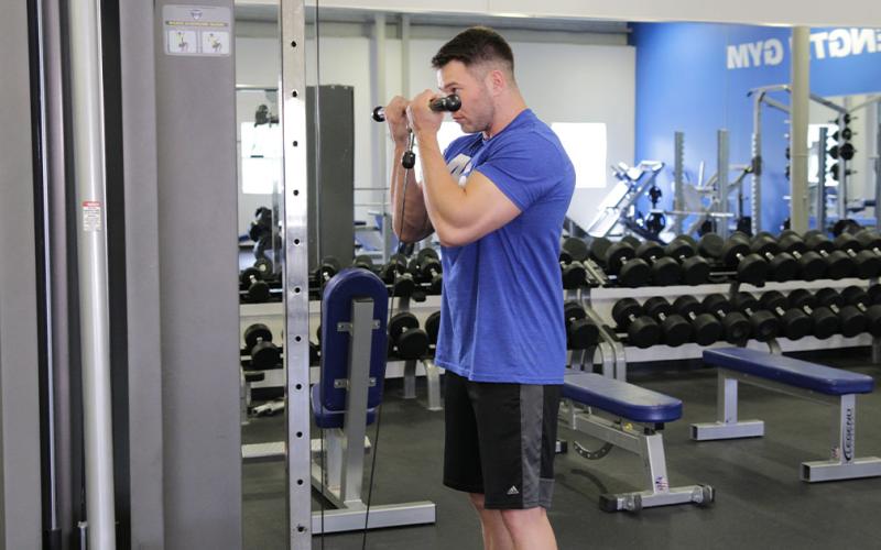 Fit man doing a close grip cable curl in the gym.