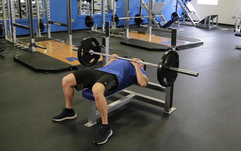 Fit man doing a close grip chest press in the gym.