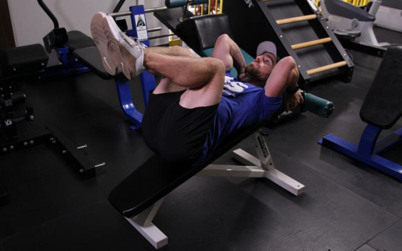 Fit man doing a Decline Bench Knee Raise in the gym.