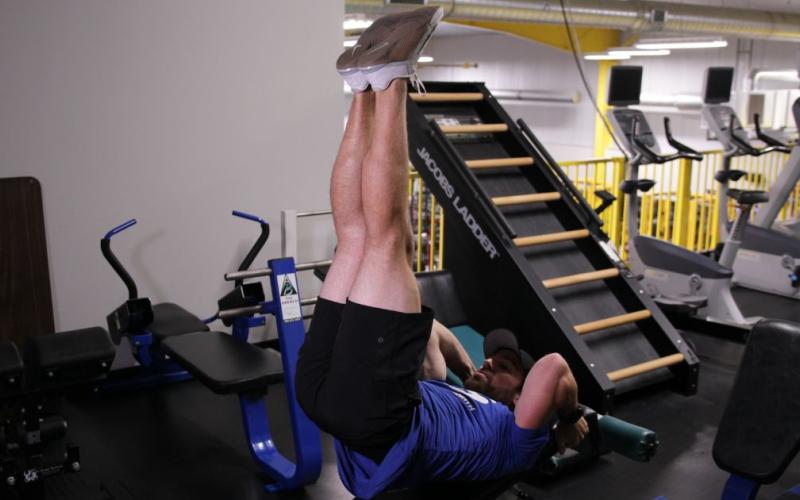 Fit man doing a Decline Bench Leg Raise With Hip Thrust in the gym.