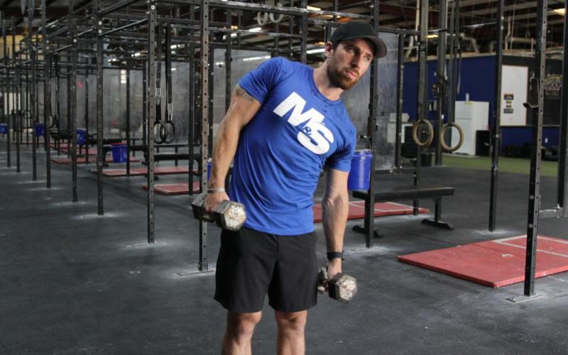Fit man doing a dumbbell side bend in the gym.