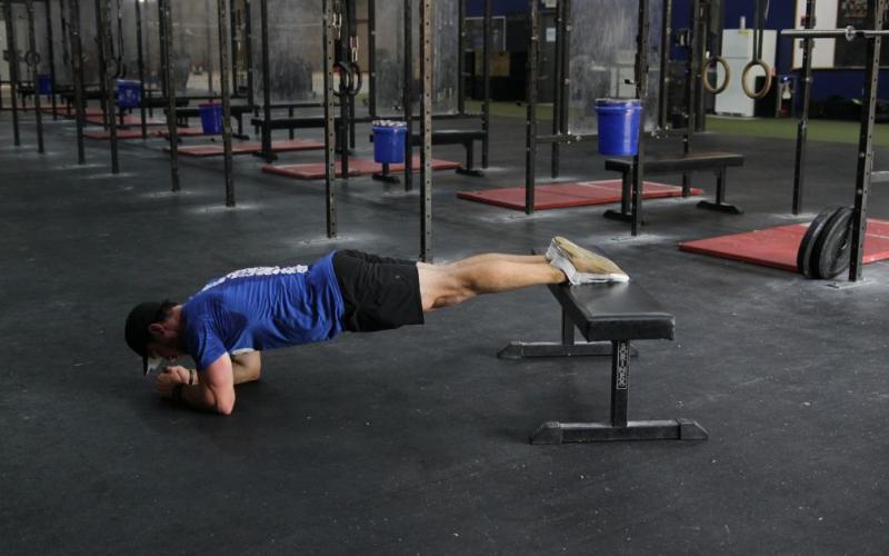 Fti man doing Feet Elevated Planks in the gym.