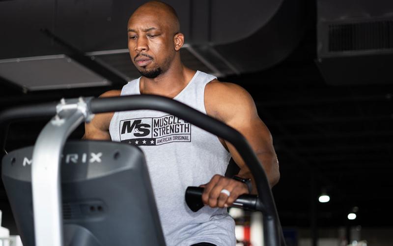 Muscular man doing cardio on the stair master at the gym.
