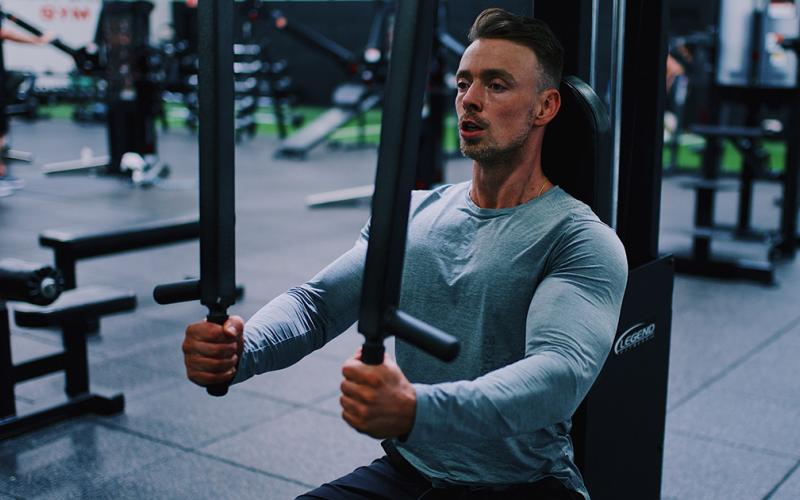 Muscular man doing machine chest flys in the gym