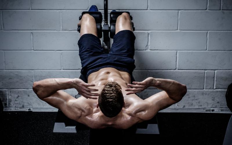 Man doing GHD sit ups in gym.