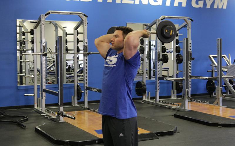 Fit man doing a french press in the gym.