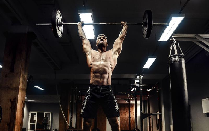 Man in gym performing overhead barbell press