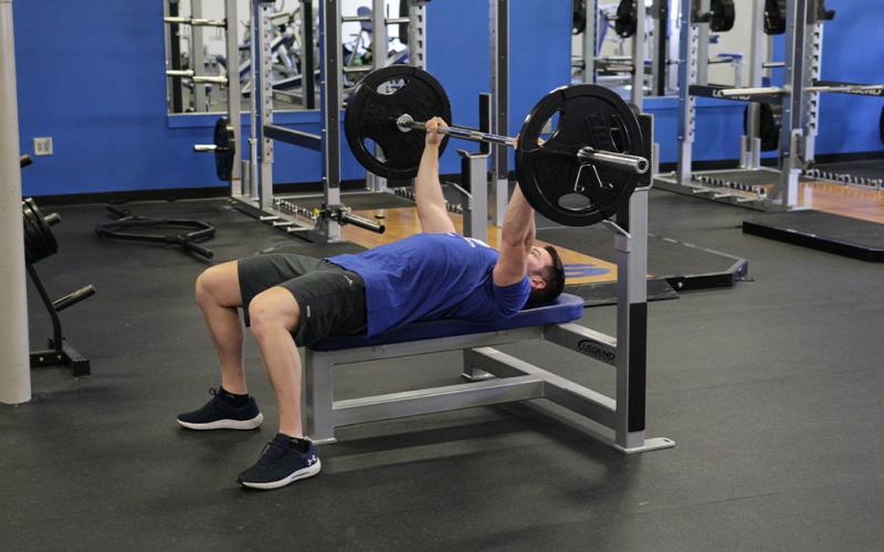 Fit man doing a guillotine press in the gym.