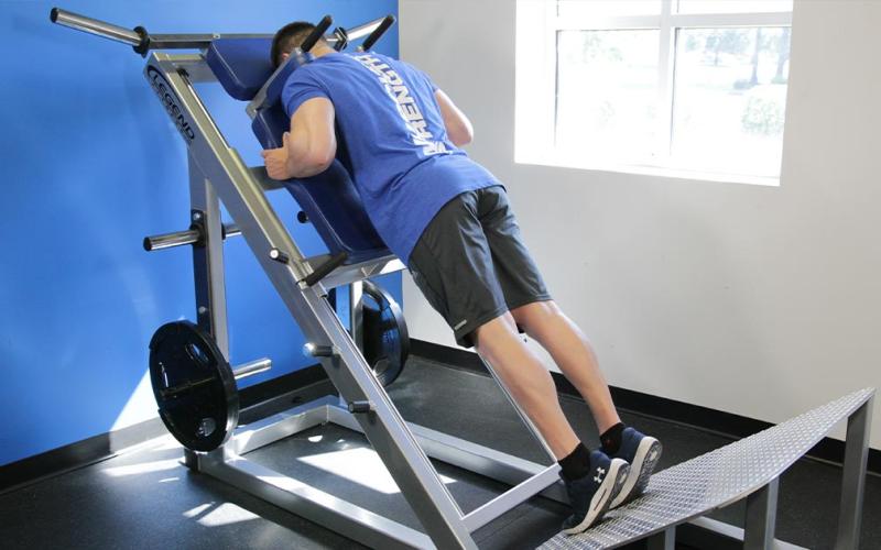Fit man doing a hack squat calf raise in the gym.