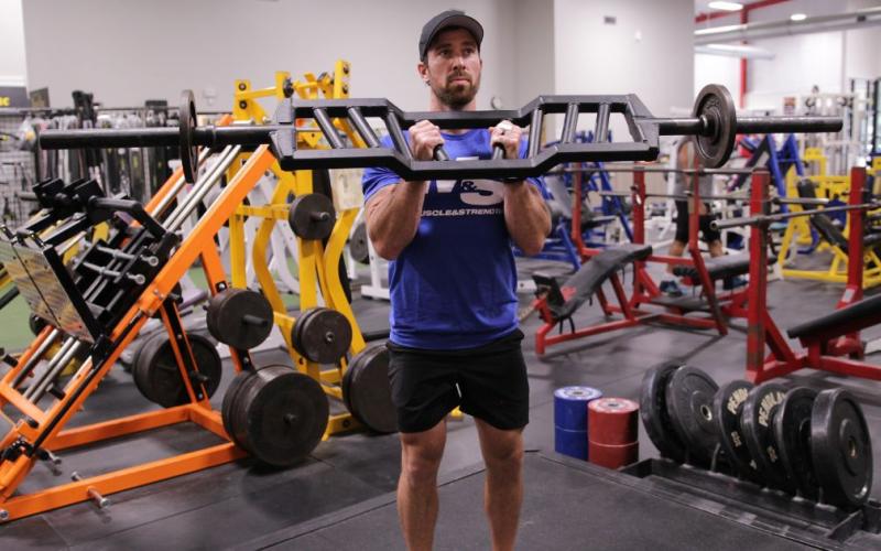 Fit man doing a hammer bar curl in the gym.