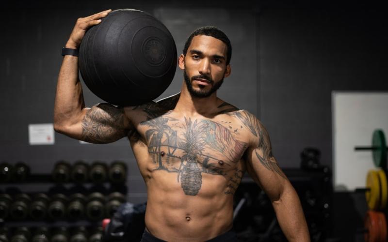 Front shot of a lean male athlete holding a medicine ball in the gym.