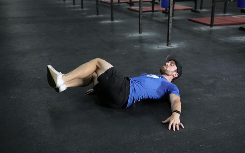 Fit man doing Lower Abdominal Hip Rolls in the gym.