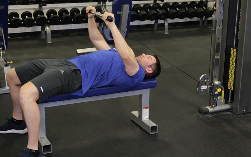 Fit man doing a lying cable pullover in the gym