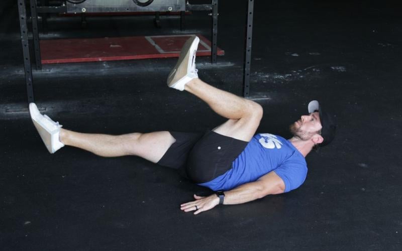 Fit man doing a Lying Alternating Knee Raise in the gym.