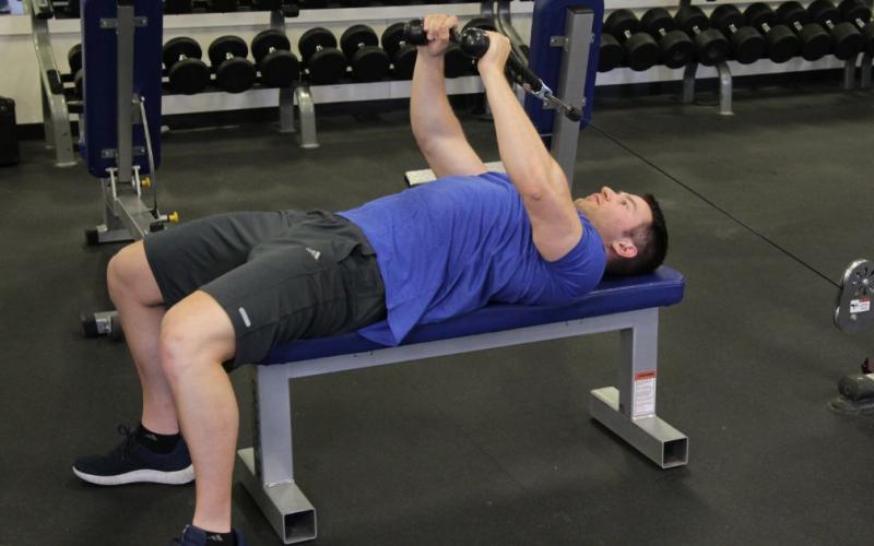 Fit man doing a lying cable pullover with rope extension in the gym