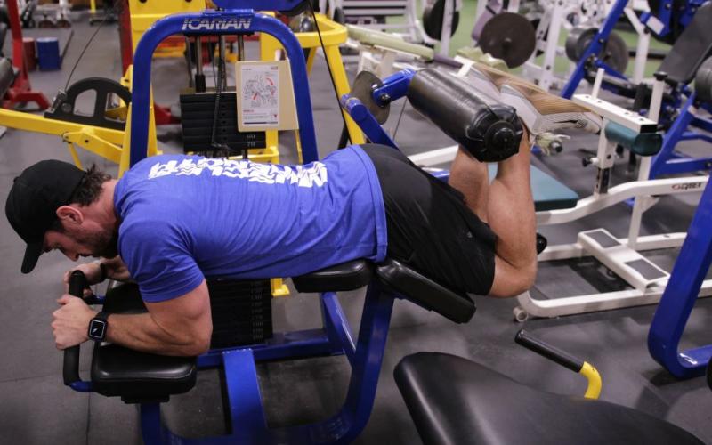 Fit man doing a lying leg curl in the gym.