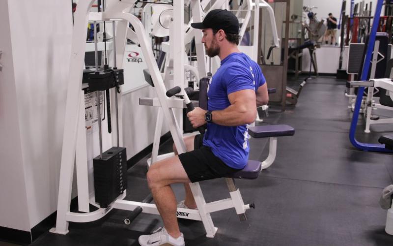 Fit man doing a machine row in the gym
