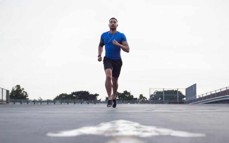 Front shot of man wearing a blue shirt running outside