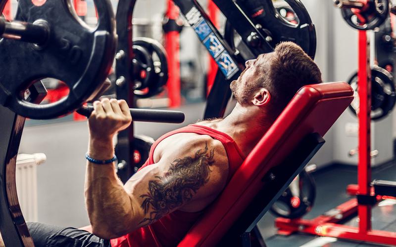 Muscular man using chest press in the gym
