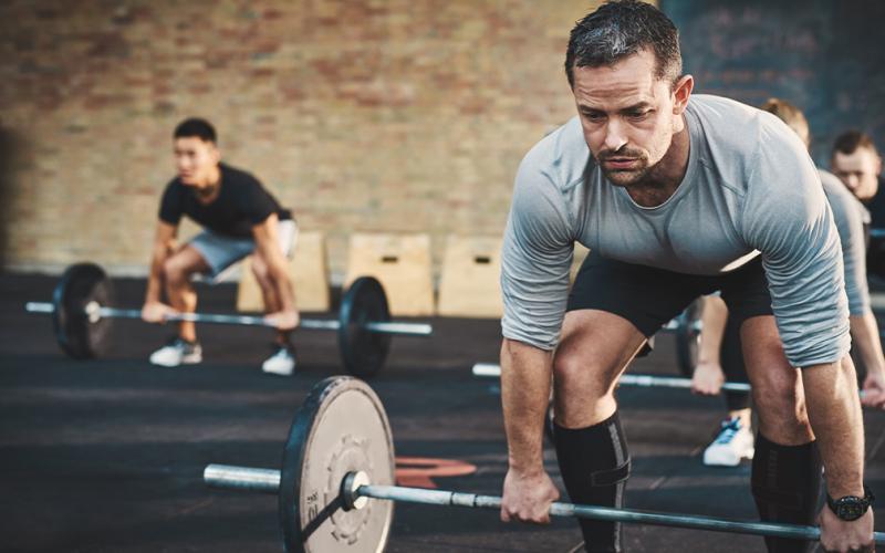 Older man doing deadlifts in the gym.