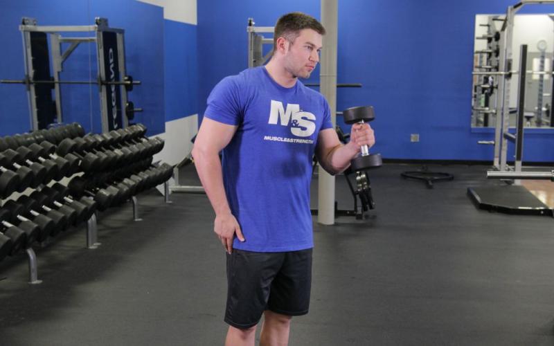 Fit man doing a One-Arm Standing Hammer Curl in the gym