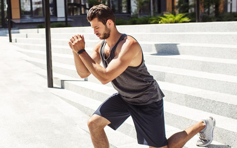 Active man doing bodyweight lunges outdoors in summer period. 
