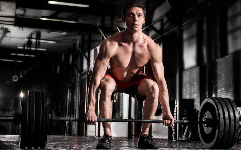 Man doing deadlifts in CrossFit style gym.